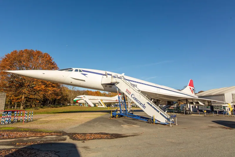A Concorde parked in the open at Brooklands Museum, needle nose to the left, with mobile airstairs at its forward door
