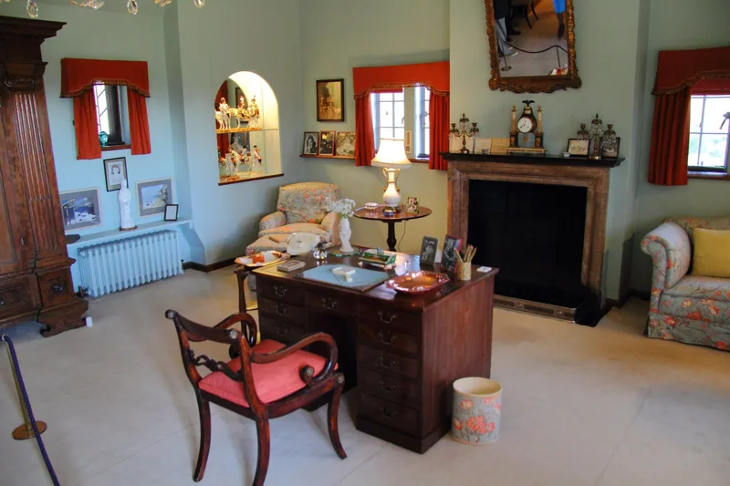 Churchill's study at Chartwell, with his mahogany desk, red-seated chair and family photographs on the mantelpiece
