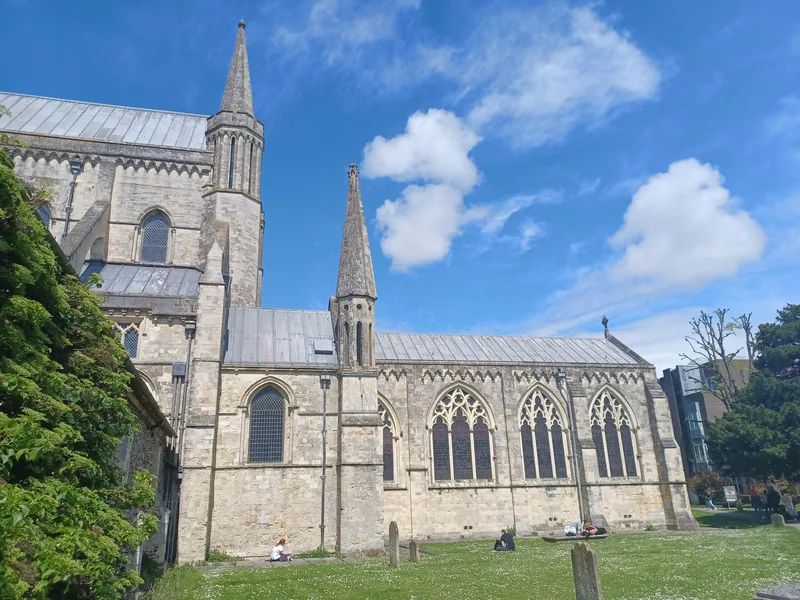 Chichester Cathedral from the south, its long nave roof and slender spire above tall Gothic windows