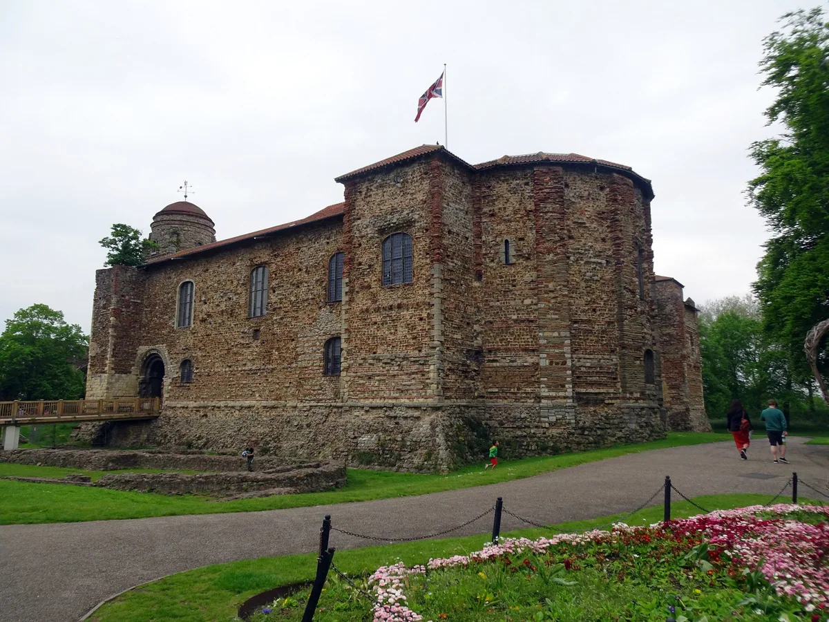 The squat Norman keep of Colchester Castle, built of Roman brick and rubble, above the flowerbeds of Castle Park