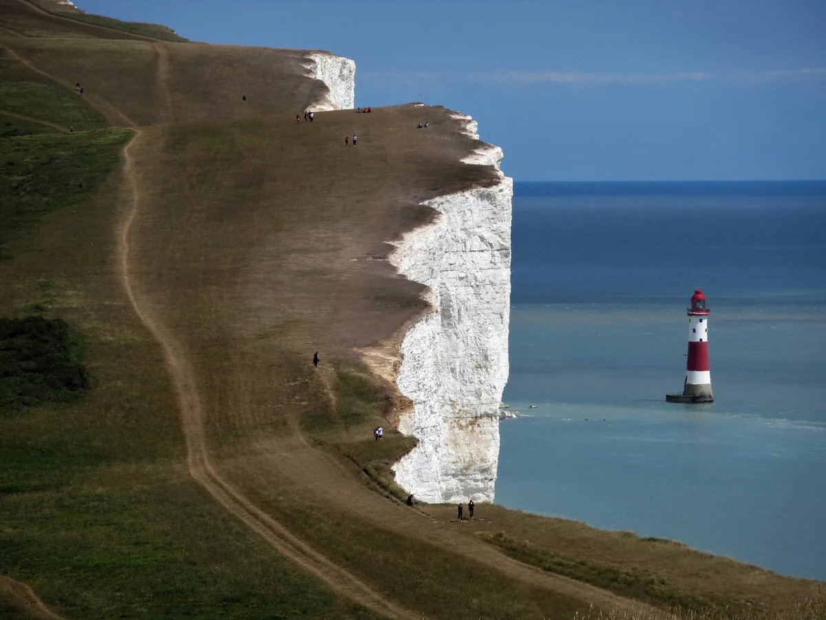 The white chalk cliff at Beachy Head dropping to the red and white lighthouse in the sea