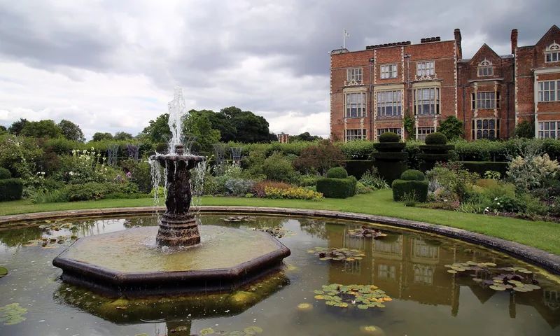 A tiered fountain in a lily pond in the gardens at Hatfield House, the brick house behind
