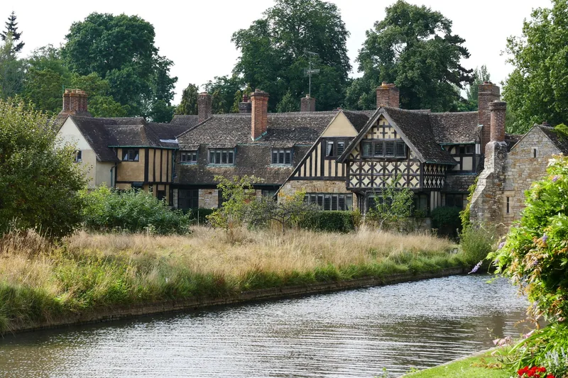 Half-timbered Tudor-style ranges at Hever Castle seen across the reed-fringed moat on a sunny day