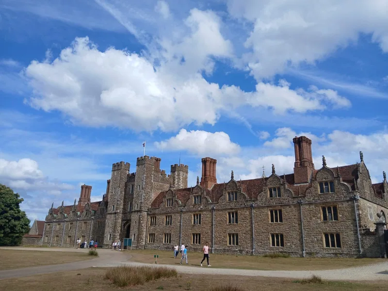 Visitors walking up the path to the gatehouse of Knole under summer cloud