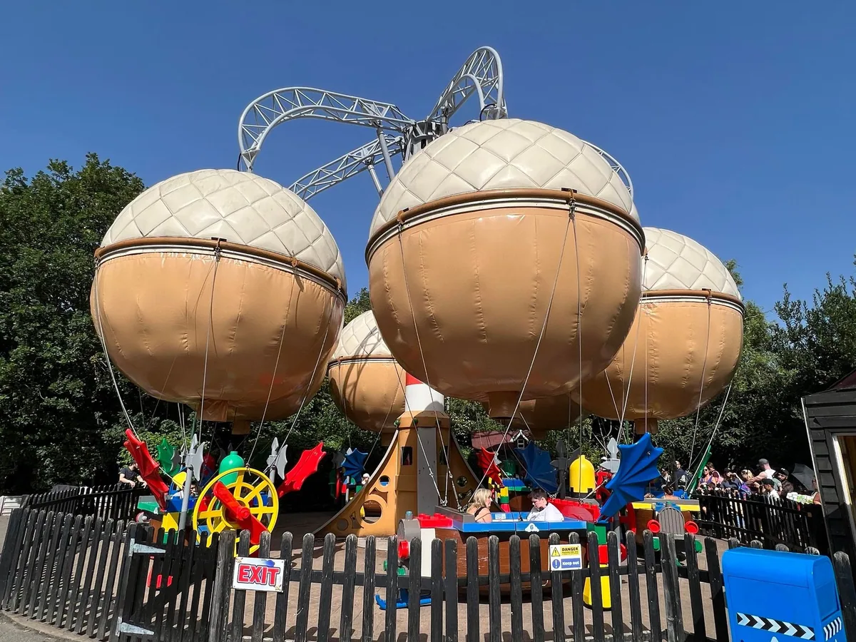 The balloon ride at Legoland Windsor, with rollercoaster track behind it under a blue sky