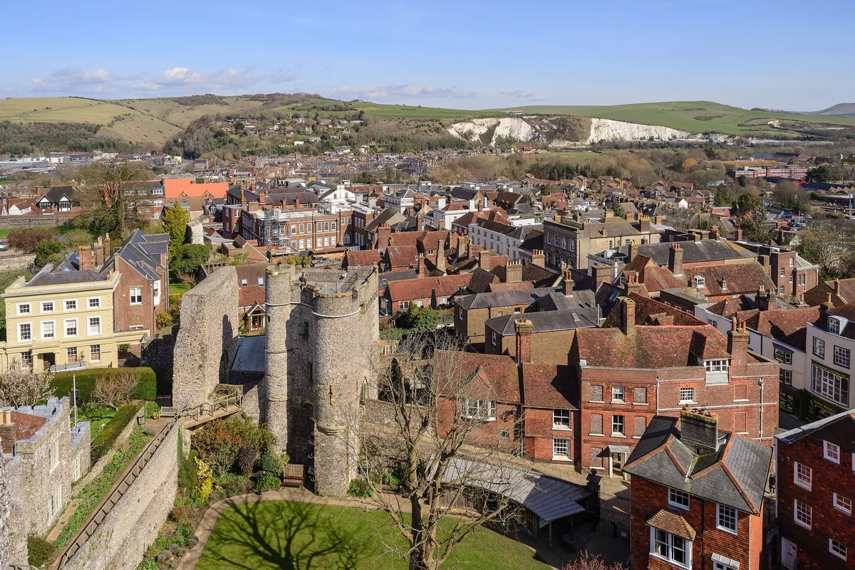 Lewes rooftops seen from the castle, with the barbican towers in the foreground and the chalk South Downs beyond