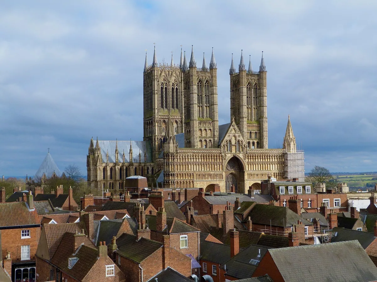 Lincoln Cathedral's twin west towers and carved west front rising above the red-tiled roofs and chimneys of the old city