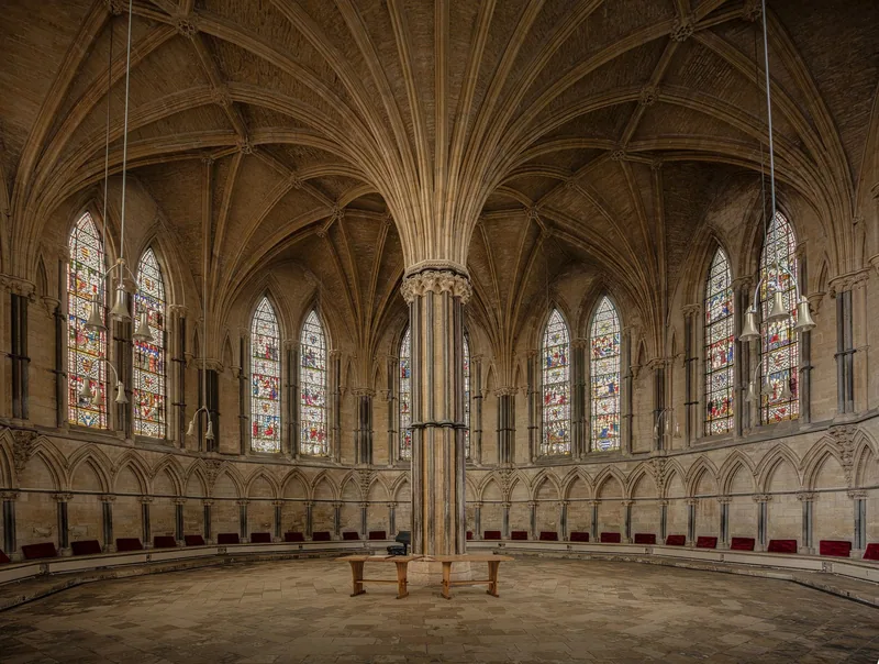 Inside Lincoln Cathedral's chapter house: vaulting ribs fanning from a central pier, stained glass and red seats round the wall
