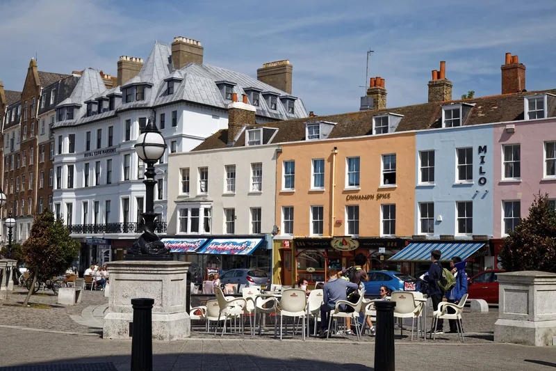 Pastel-painted houses and cafe tables on The Parade in Margate Old Town on a bright day