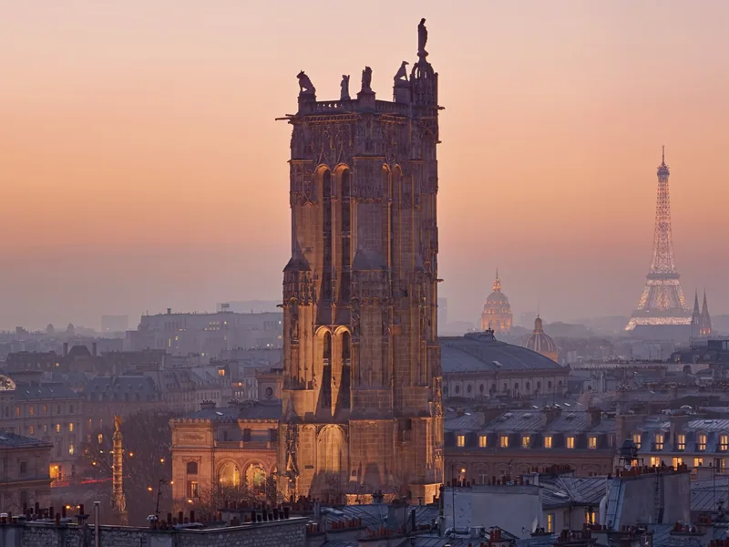 The Tour Saint-Jacques above the Paris rooftops at dusk, with the Eiffel Tower on the skyline behind