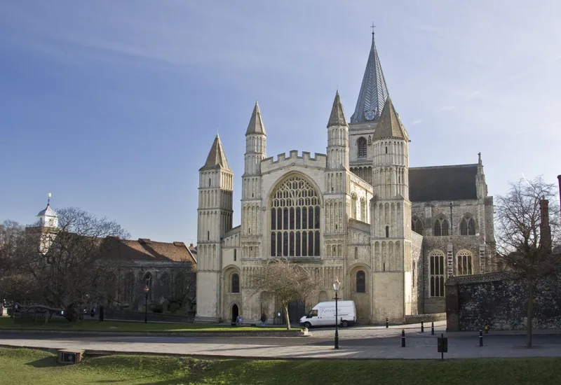 The west front of Rochester Cathedral with its spire, seen across the green