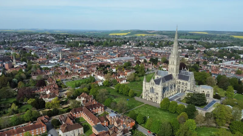 Salisbury Cathedral and its tall spire seen from the air, with the close and the rooftops of the city around it