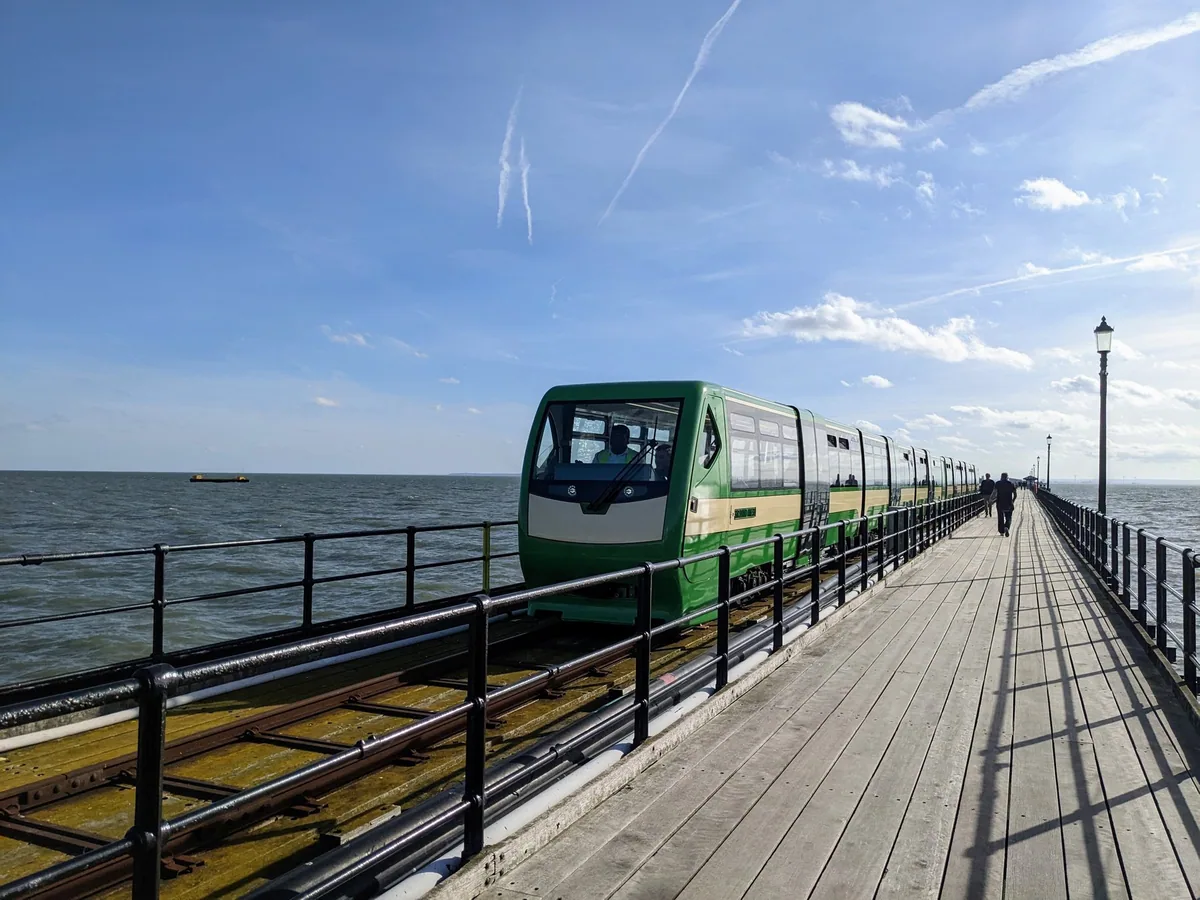 The green pier train running along the timber deck of Southend Pier, with the Thames Estuary on both sides