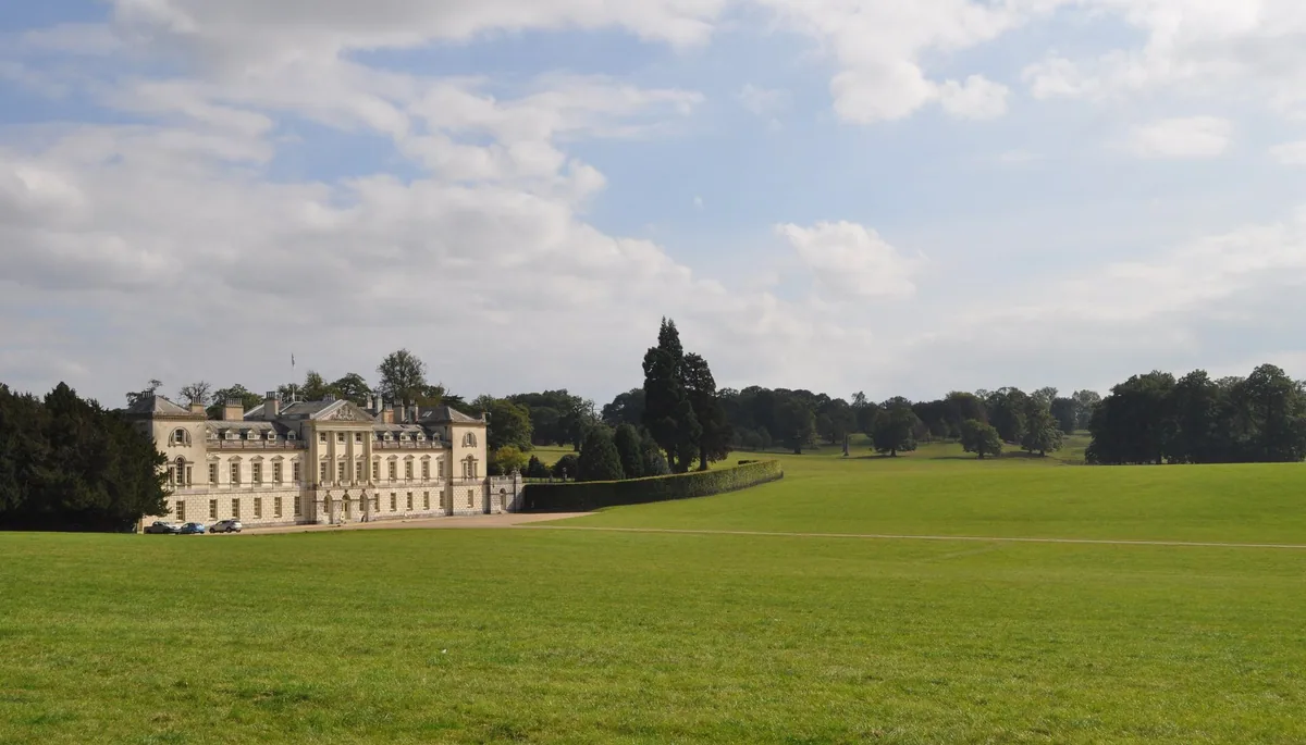 Woburn Abbey seen across its parkland, a long classical house behind open grass