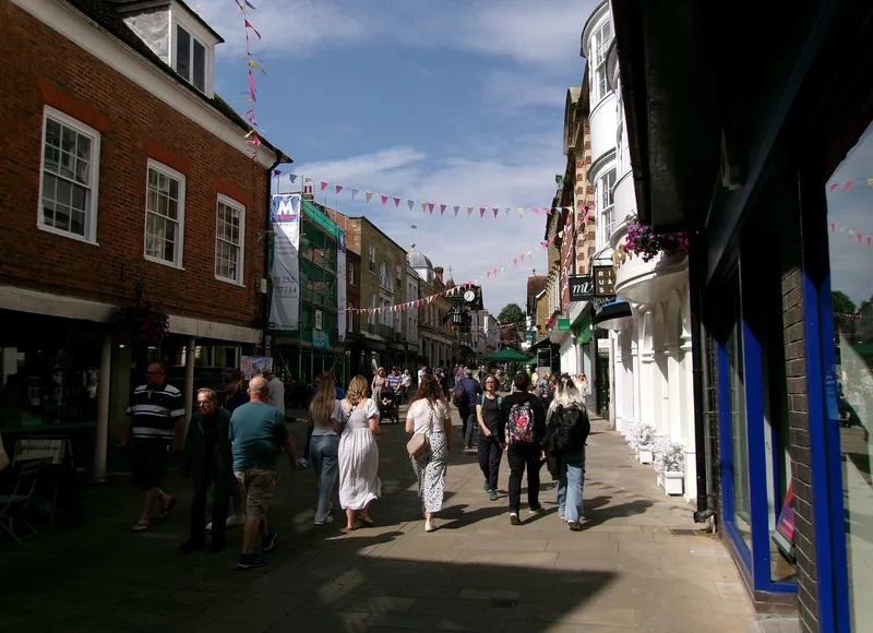 Shoppers on Winchester's pedestrianised High Street, with bunting strung between the shopfronts