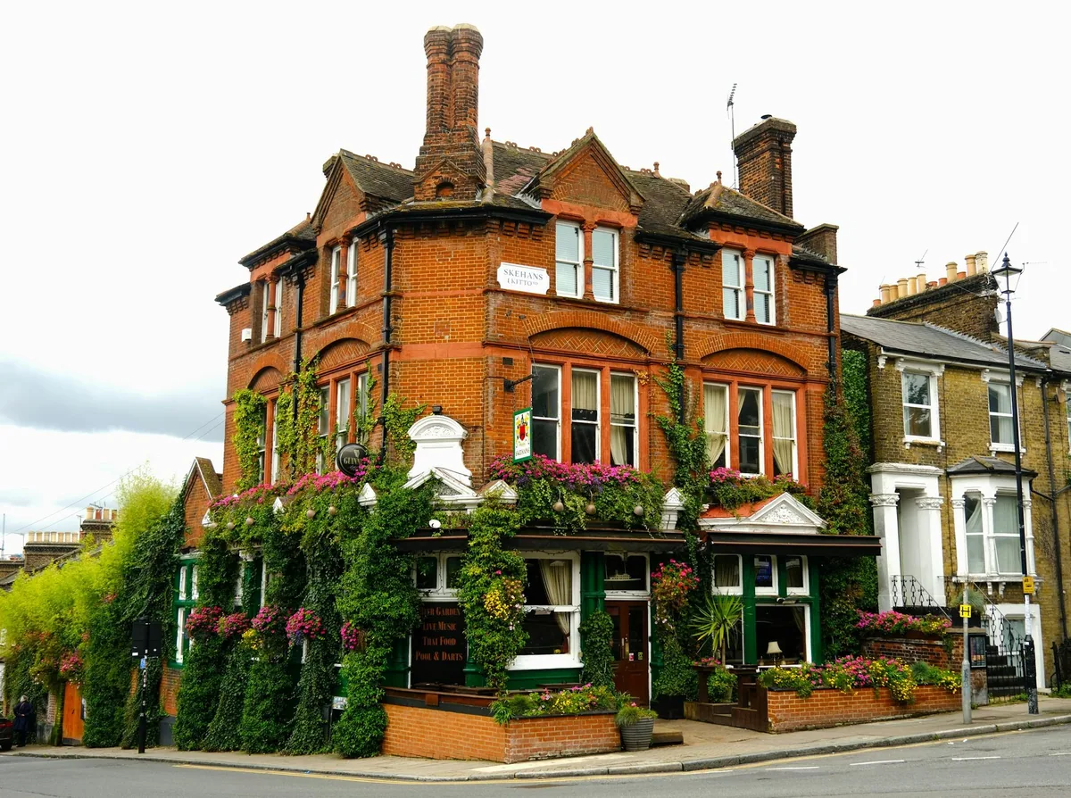 A red-brick Victorian pub covered in climbing plants and hanging baskets on a street corner in Telegraph Hill