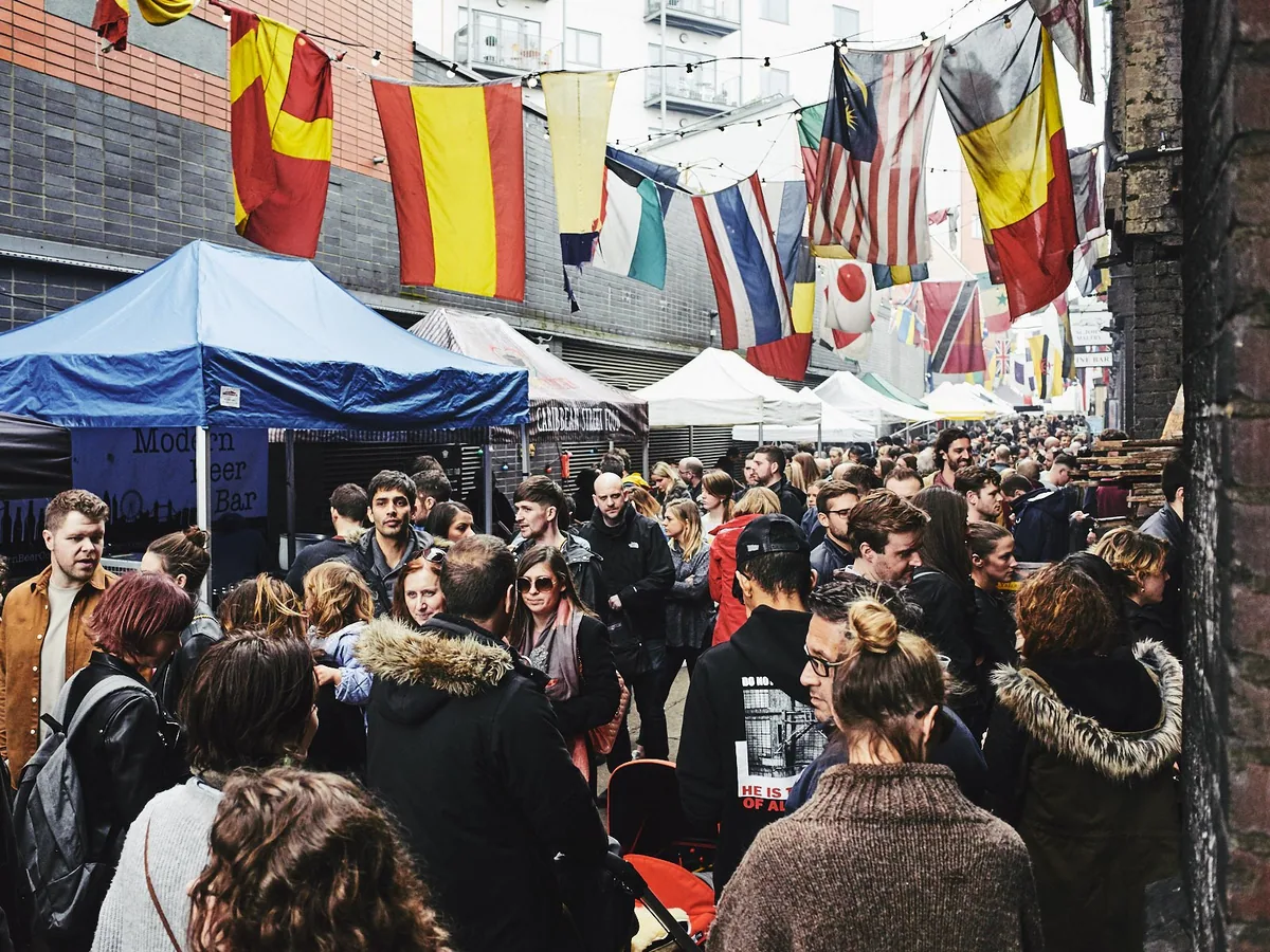 Crowds under strings of bunting at the Ropewalk market on Maltby Street, with stalls and a beer bar along the railway arches