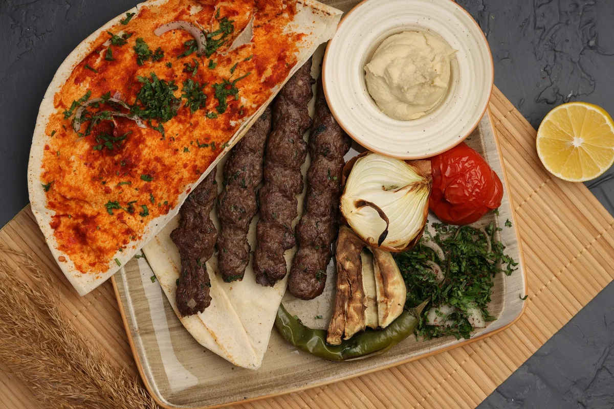 A platter of grilled kofta kebabs with flatbread, garlic sauce, grilled peppers and aubergine