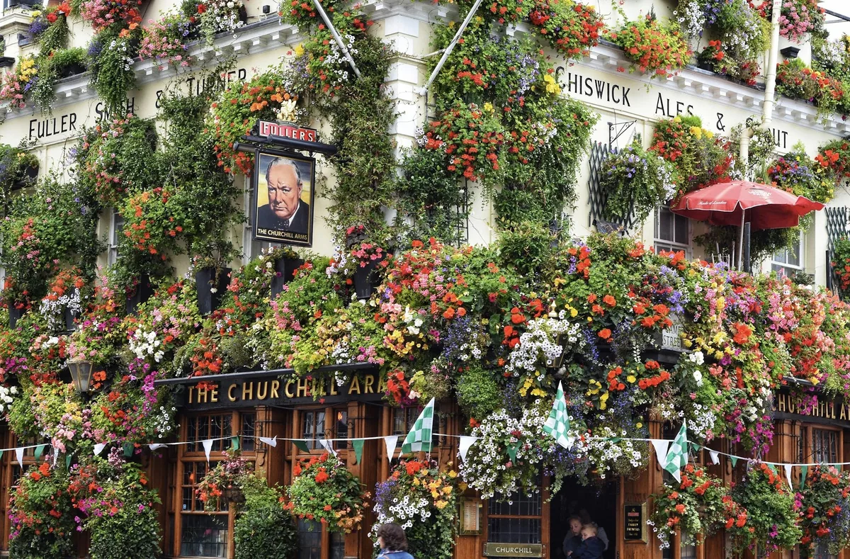 The flower-covered front of the Churchill Arms pub in London, with hanging baskets on every window