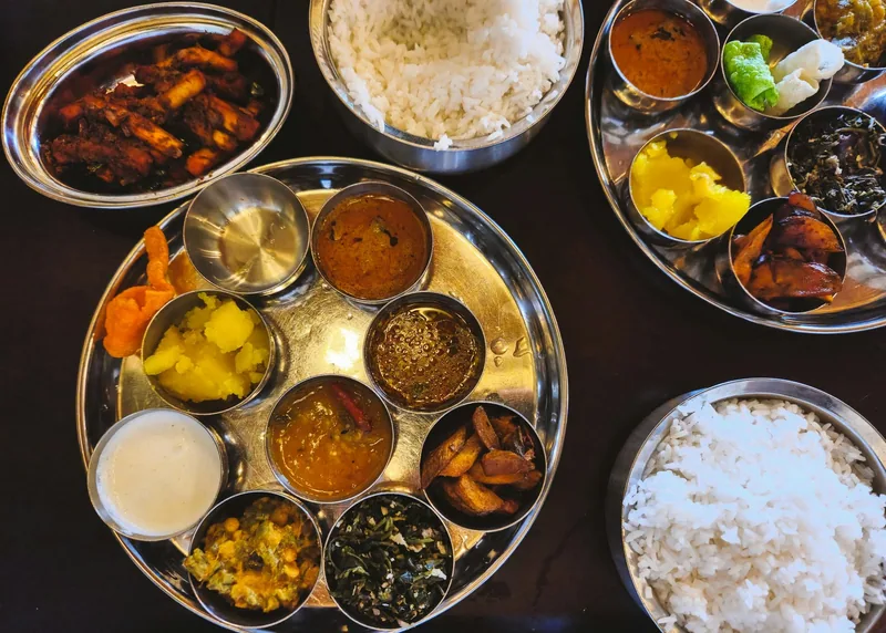 Two vegetarian thalis laid out with rice and small bowls of curries, chutneys and pickles