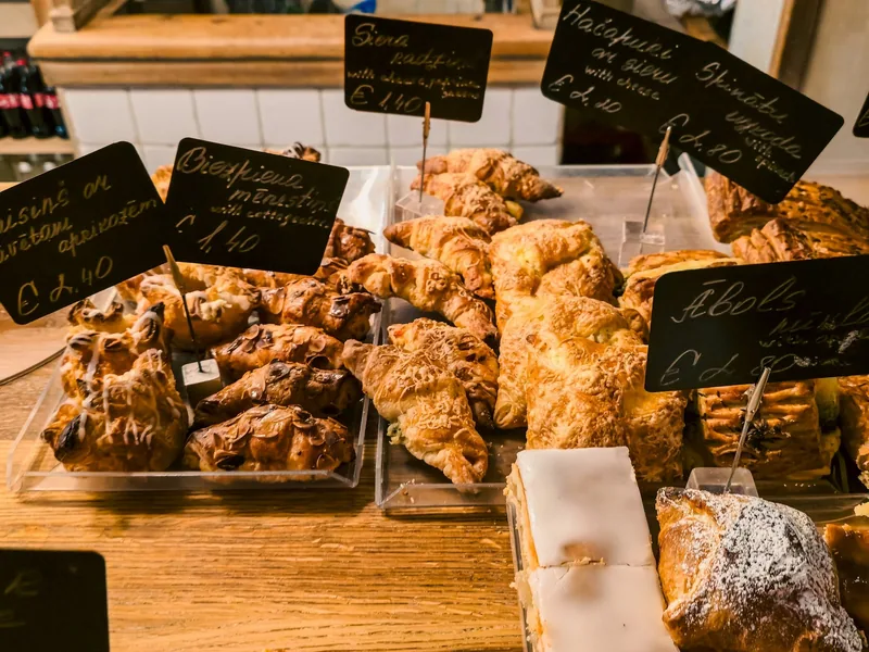Golden pastries piled on a wooden bakery counter with handwritten chalkboard price tags