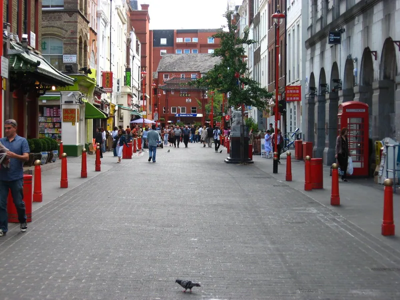 The pedestrianised end of Gerrard Street with red bollards and a red phone box, the Chinatown gate in the distance
