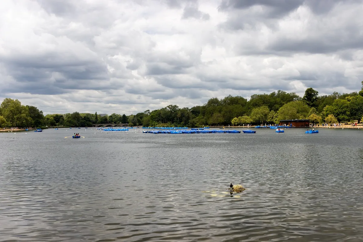 Pedalos and rowing boats on the Serpentine in Hyde Park under a cloudy summer sky