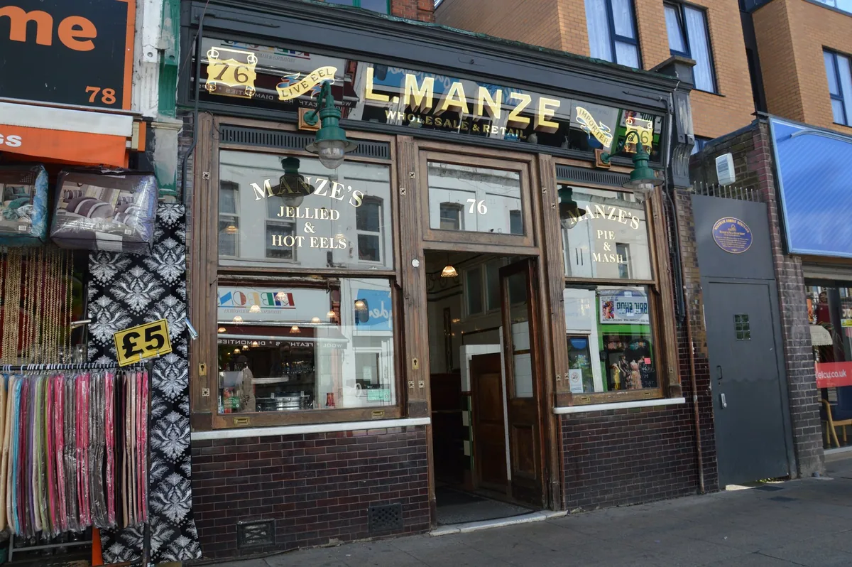 Tiled Edwardian frontage of L. Manze eel, pie and mash shop with gold lettering above the windows