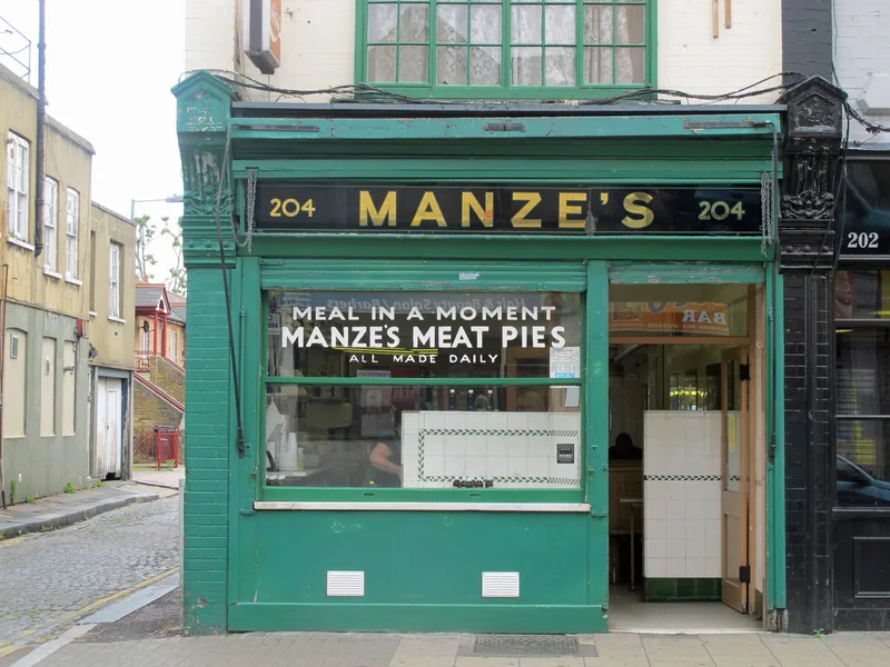 Green-tiled shopfront of Manze's pie shop on Deptford High Street, meat pies painted on the window
