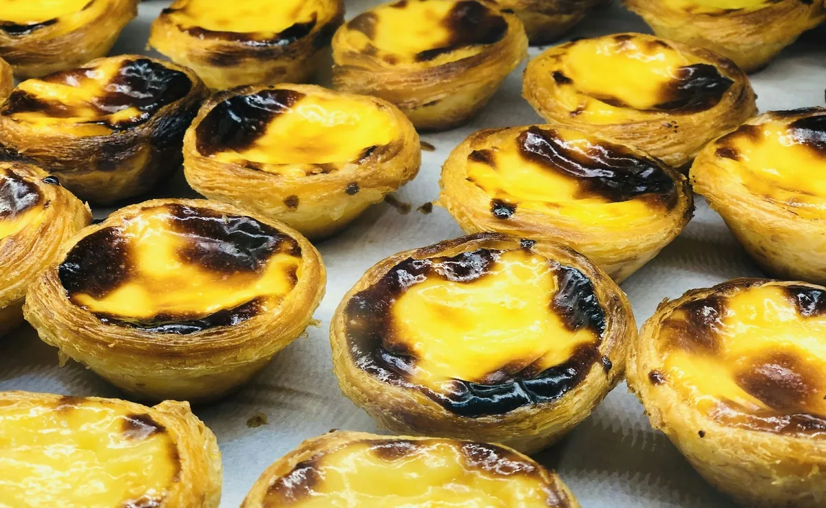 Rows of pasteis de nata, the Portuguese custard tarts, with blistered caramelised tops