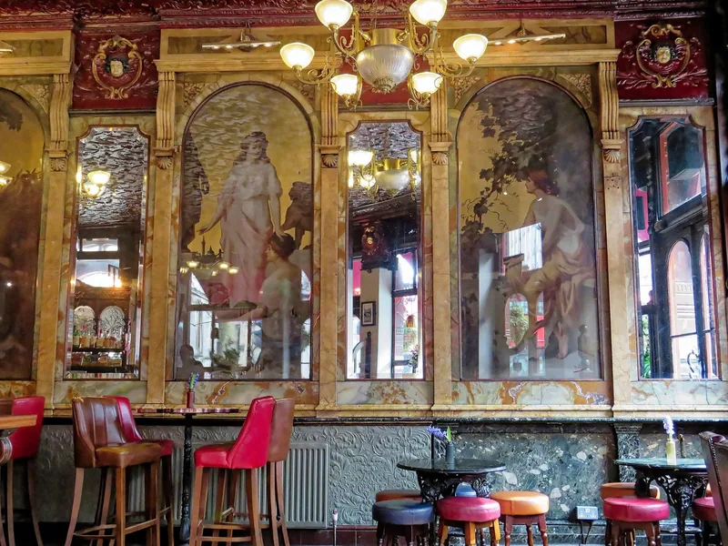 Painted panels and etched mirrors above the bar stools of a Victorian London pub