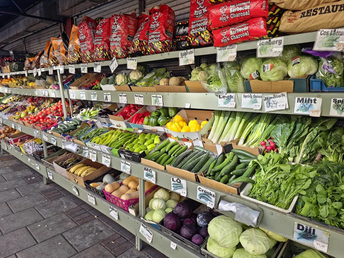 Shelves of fruit and vegetables with handwritten pound prices outside a London shop
