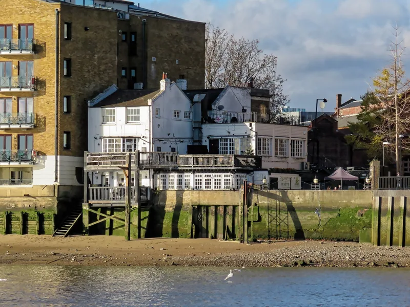 The Prospect of Whitby seen from the River Thames at low tide, standing on timber piles above the foreshore