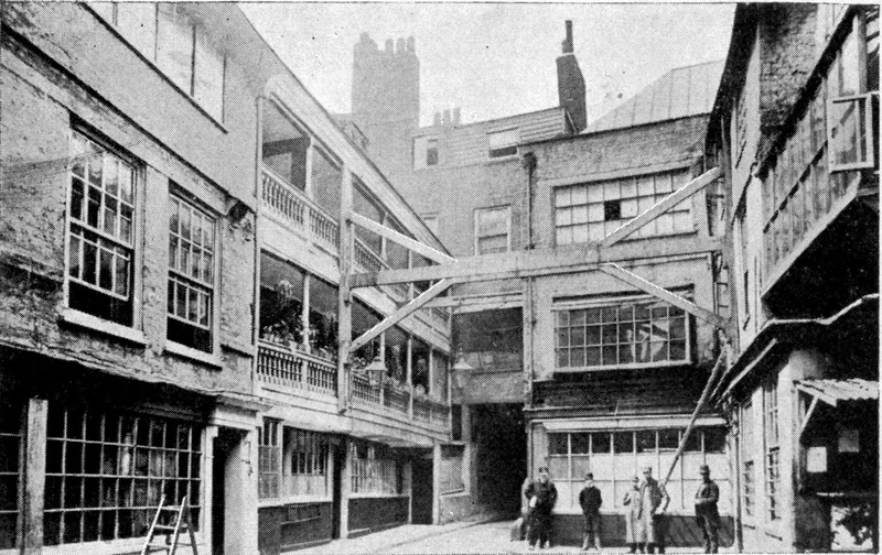 A photograph of the George Inn's yard in 1889, the wooden galleries propped with diagonal timber braces and a few men standing below