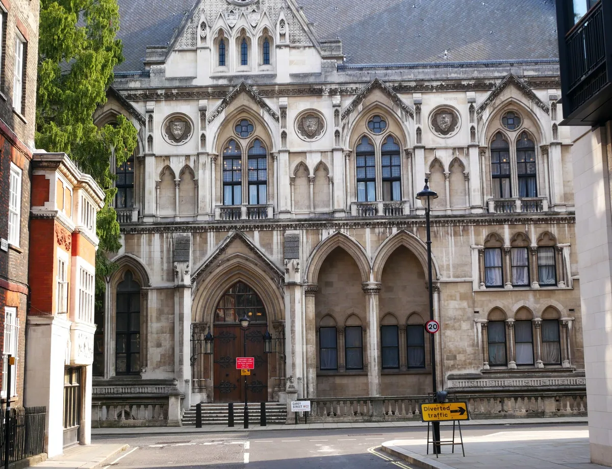 The Gothic north front of the Royal Courts of Justice on Carey Street, pointed arcades and a studded timber door above an empty pavement