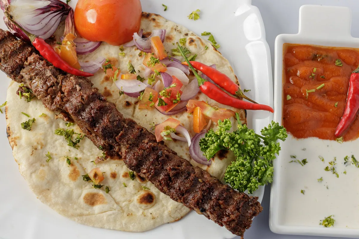 A long grilled kebab served on flatbread with roast tomato, chillies, red onion and parsley