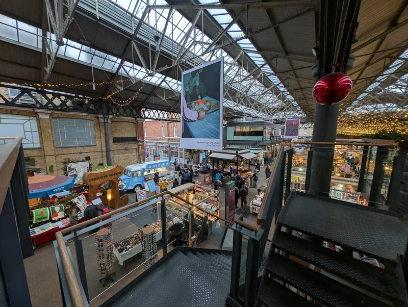 Old Spitalfields Market seen from a staircase, food stalls under the glass roof