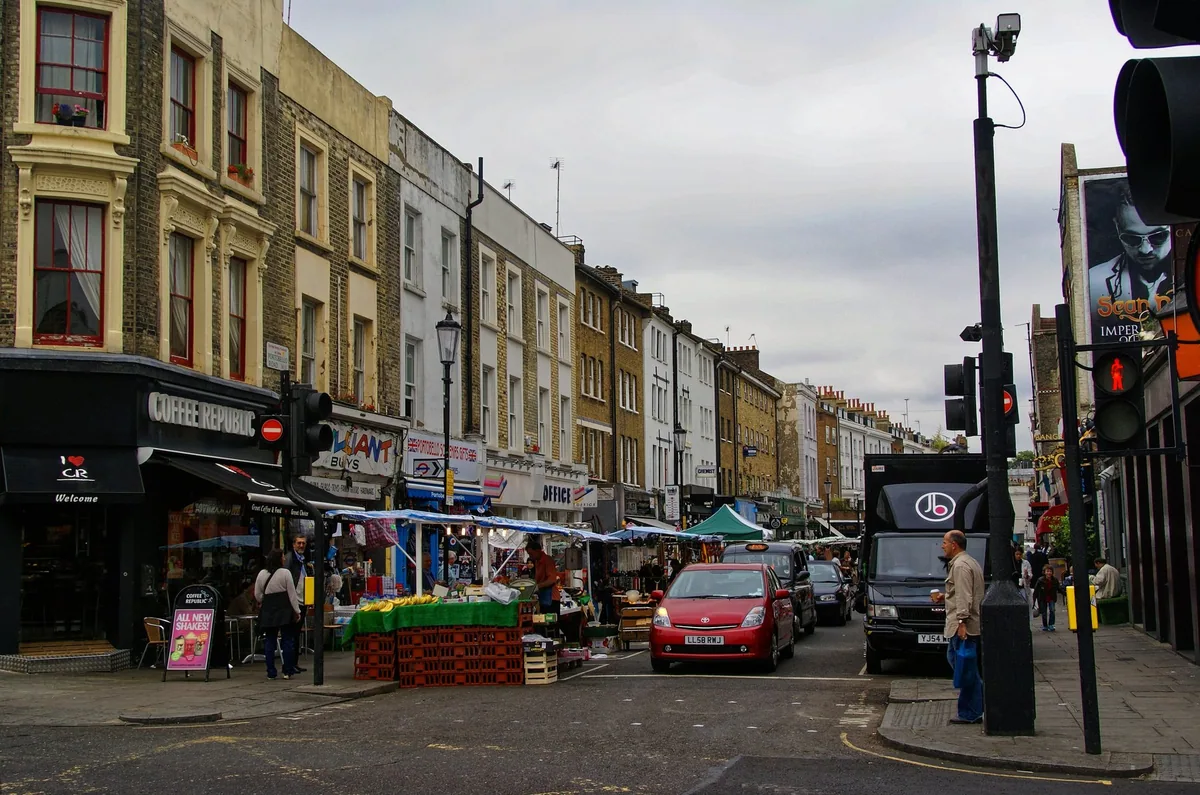 Portobello Road with fruit stalls, cafes and terraced shopfronts on a grey day