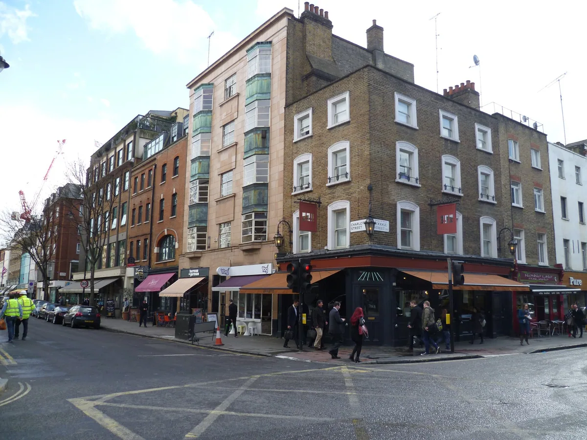 The corner of Charlotte Street and Goodge Street in Fitzrovia, lined with restaurant awnings and pavement tables