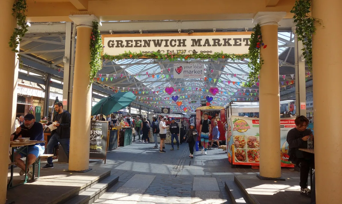The Greenwich Market entrance with its painted sign and bunting, looking in at the food stalls under the glass roof