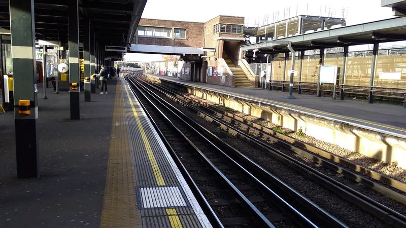 Tracks and open platforms at Wembley Park Underground station in winter sunlight, with the footbridge stairs beyond