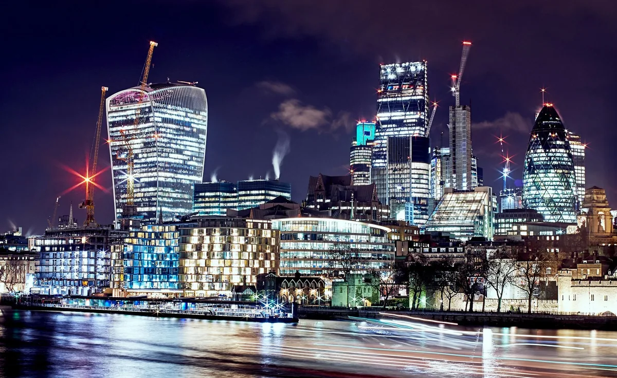 The illuminated skyscrapers of the City of London reflected in the Thames on a clear night
