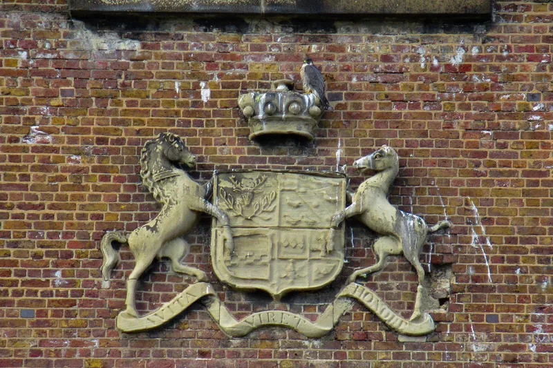 A carved coat of arms with two horse supporters set into the brick of the Wharncliffe Viaduct, a peregrine falcon perched above it