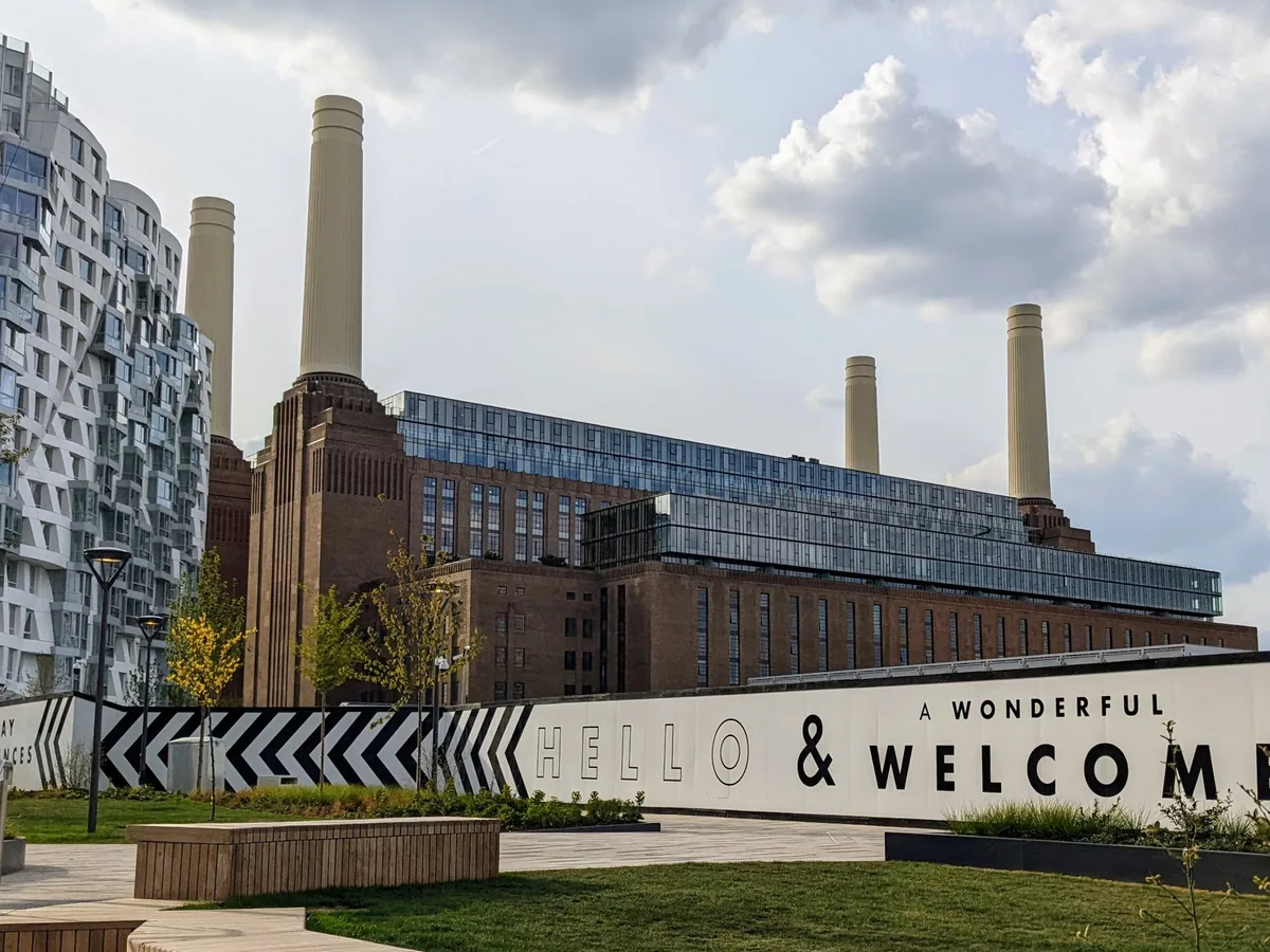 Battersea Power Station's four white chimneys above its brick flanks, with new flats alongside