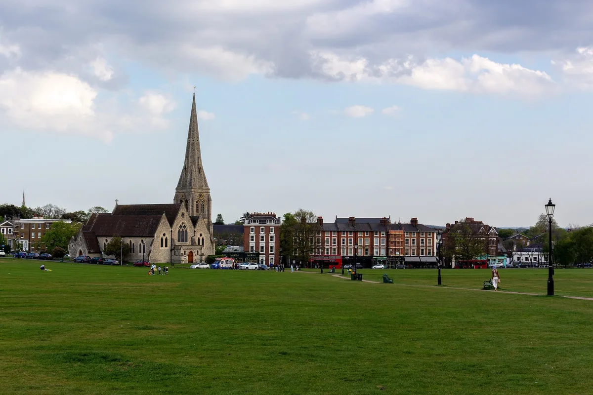 The open grass of Blackheath with the spire of All Saints church and the village beyond