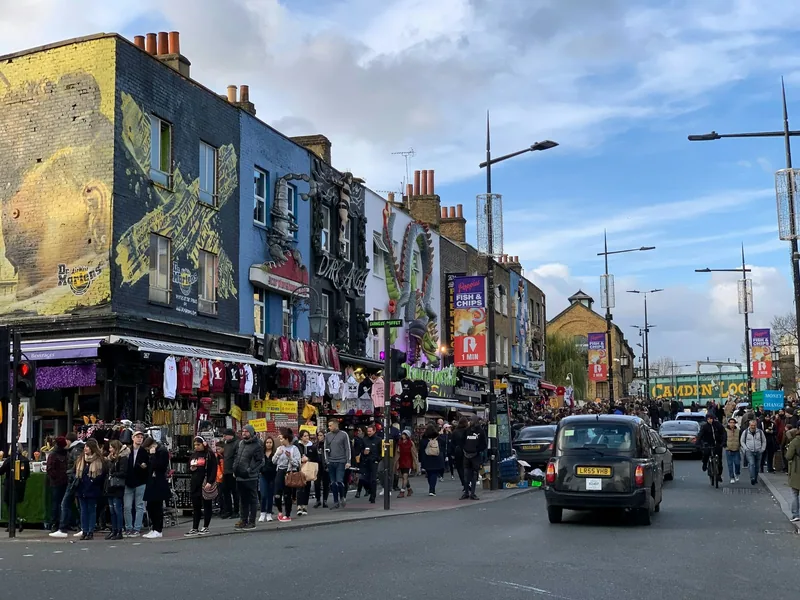 Crowds passing decorated shopfronts and giant sculpted signs on Camden High Street