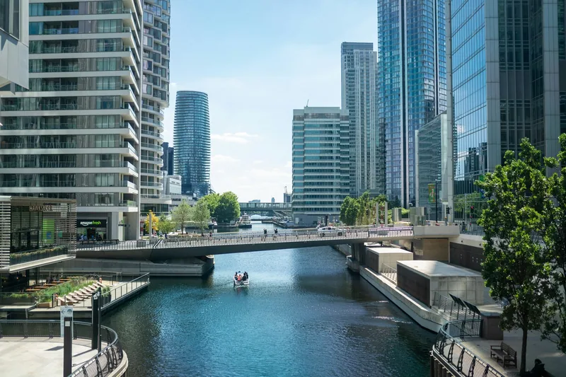 A bridge crossing the old dock water between the glass towers of Canary Wharf
