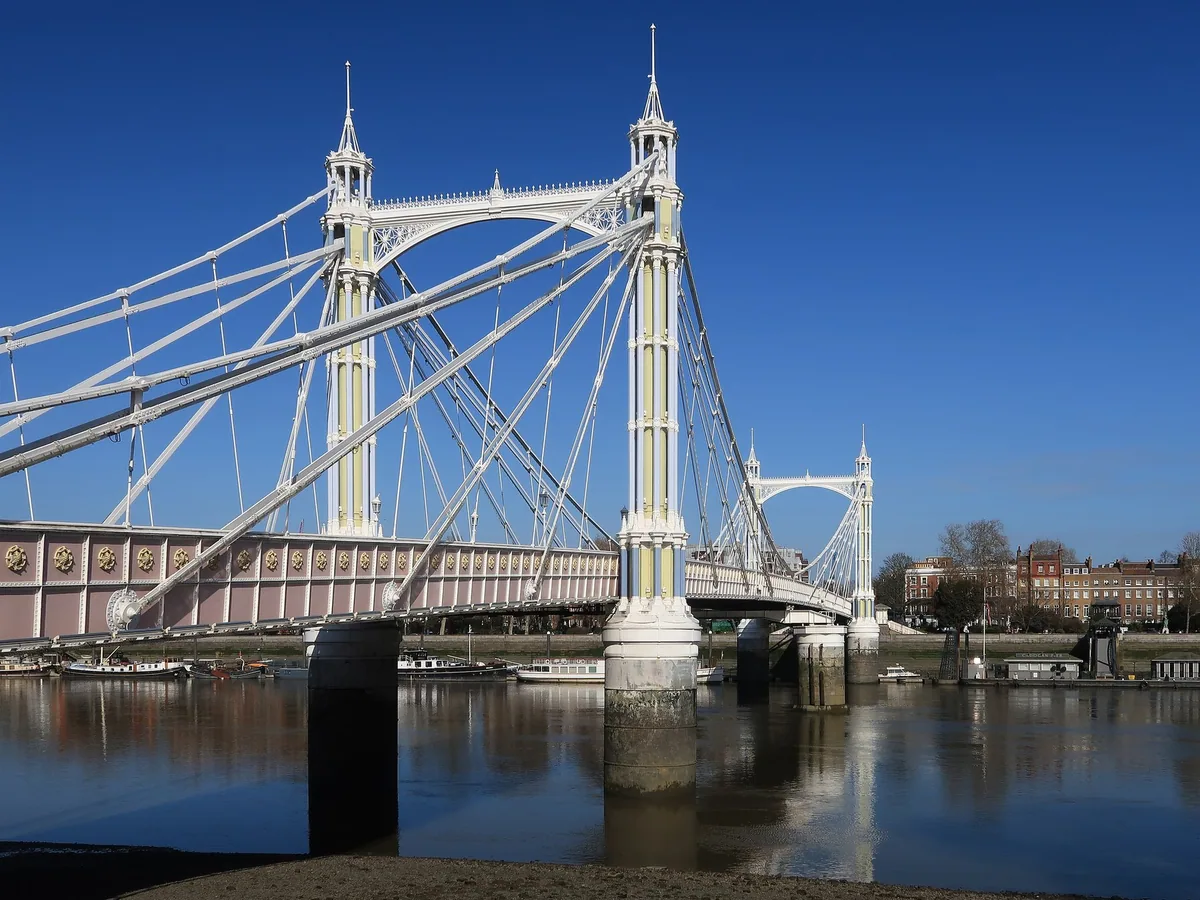 The white cables and towers of Albert Bridge crossing the Thames at Chelsea under a blue sky