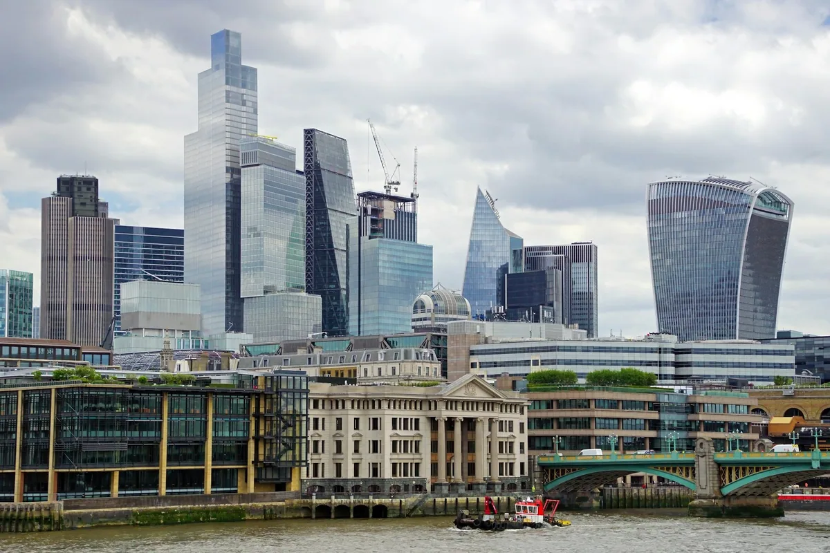 The cluster of glass towers in the City of London rising above the Thames on a cloudy day