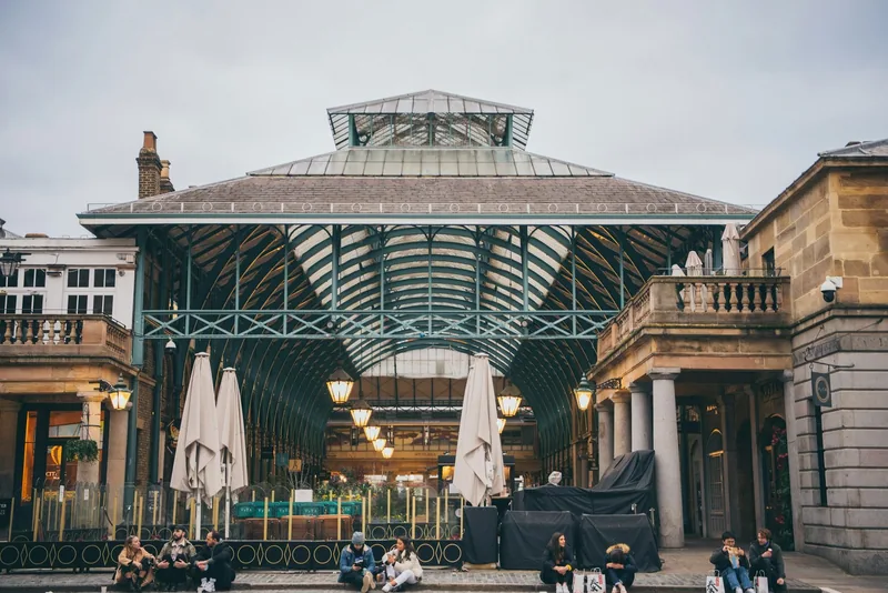 The green ironwork and glass roof of Covent Garden's market building seen from the piazza